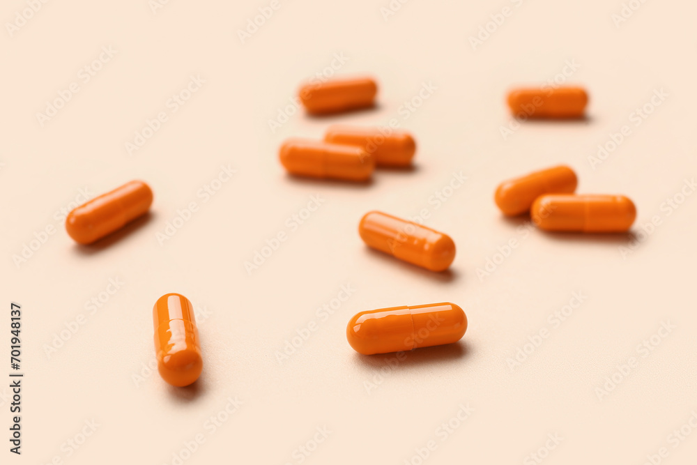 Orange medical capsules on beige background, closeup Orange medical capsules on beige background, closeup