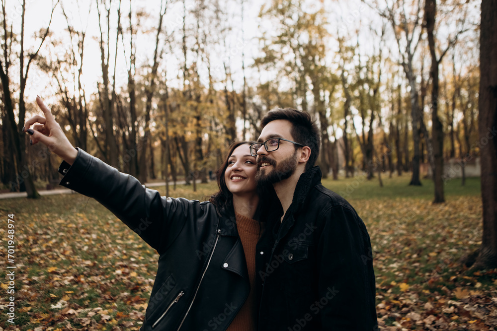 Heterosexual caucasian young loving couple walking outside in the city park in sunny weather, hugging smiling kissing laughing spending time together. Autumn, fall season, orange yellow red maple leav Heterosexual caucasian young loving couple walking outside in the city park in sunny weather, hugging smiling kissing laughing spending time together. Autumn, fall season, orange yellow red maple leav