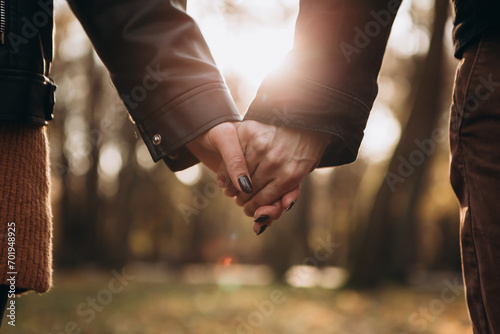 Cropped image hands young loving couple pinky swear, pinky promise hook each other's little finger, hugging smiling kissing laughing spending time together. Autumn, fall season, maple leaves photo