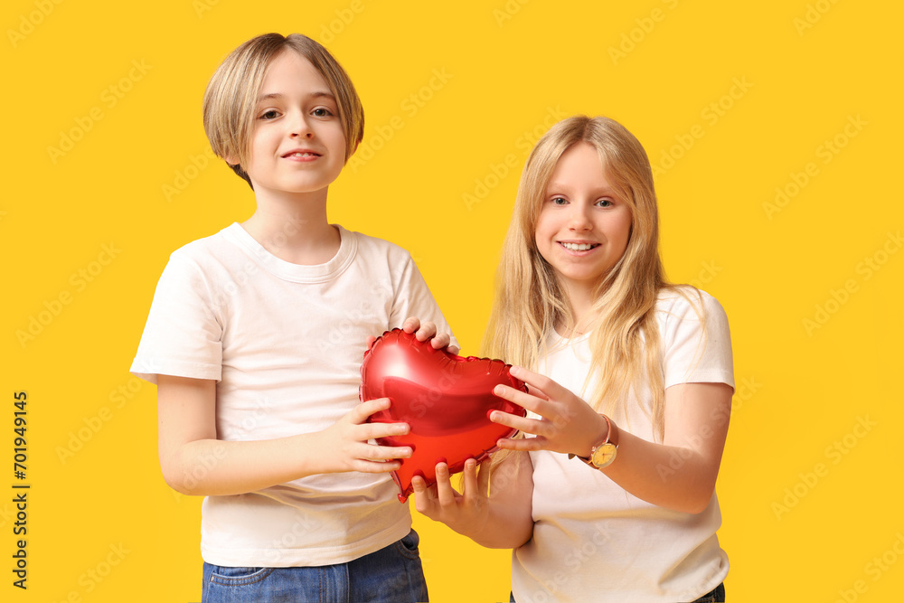 Little children with heart-shaped balloon on yellow background. Valentine's Day celebration Little children with heart-shaped balloon on yellow background. Valentine's Day celebration