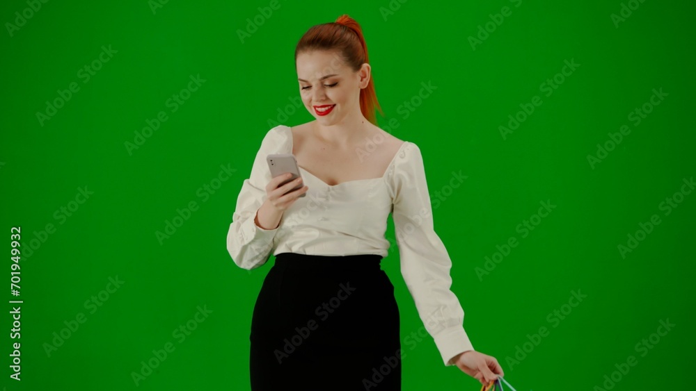 Portrait of attractive office girl on chroma key green screen. Woman in skirt walking holding gift bags and texting on smartphone, smiling face. Portrait of attractive office girl on chroma key green screen. Woman in skirt walking holding gift bags and texting on smartphone, smiling face.
