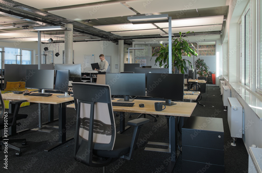 IT office with many desks and monitors and man in background. IT office with many desks and monitors and man in background.