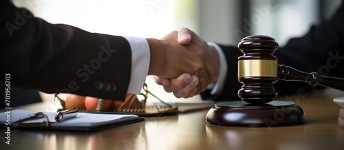 lawyer shaking hands with client on the table there is a legal gavel and legal scales