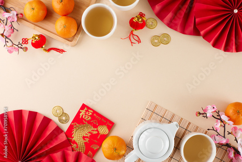 Celebrating chinese New Year with a tea ceremony. Top view photo of teapot, cups of tea, tangerines, money envelope, folding fans, sakura, gold coins on beige background with promo area