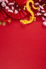 Sending happiness and prosperity this Chinese New Year 2024. Top view vertical photo of gold dragon, folding fans, traditional coins, sakura, lanterns on red background with advert zone