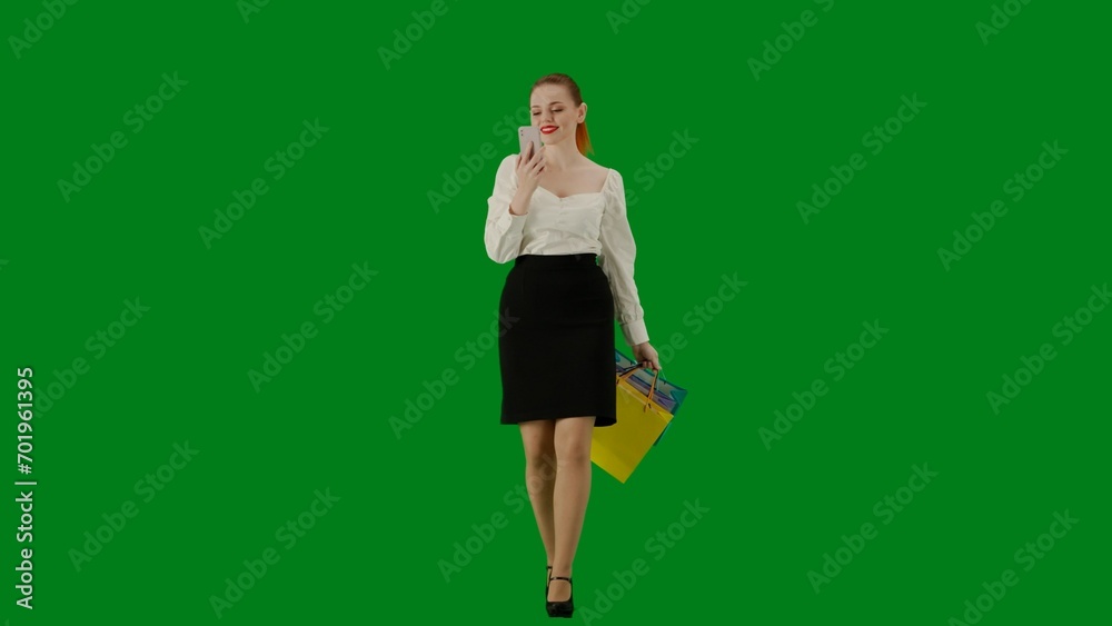 Portrait of attractive office girl on chroma key green screen. Woman in skirt walking talking on smartphone by video call, happy expression. Portrait of attractive office girl on chroma key green screen. Woman in skirt walking talking on smartphone by video call, happy expression.