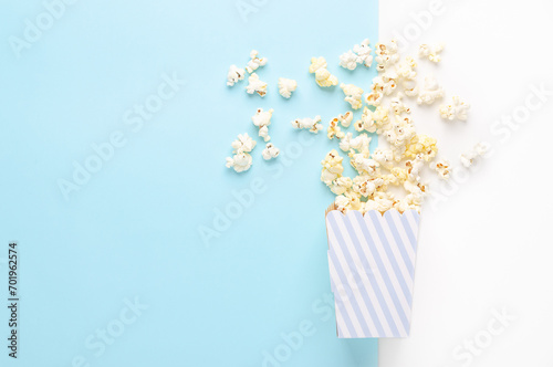 Fototapeta Naklejka Na Ścianę i Meble -  A striped bucket of popcorn on white and light blue background, top view and copy space. 