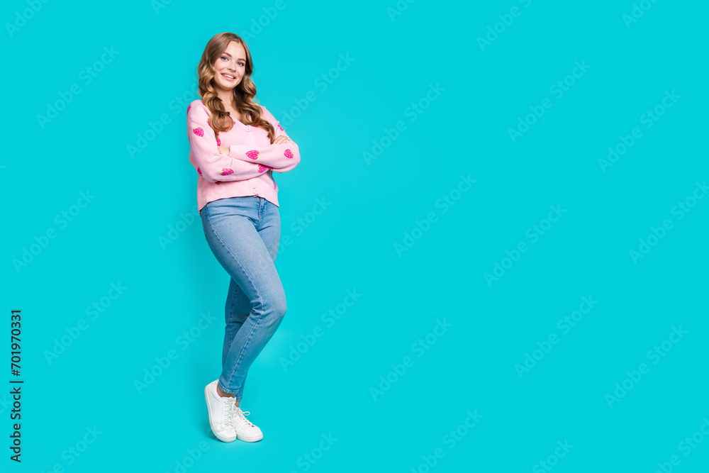 Full body length photo of woman in jeans pink strawberry print jumper folded arms posing for outlet store isolated on blue color background Full body length photo of woman in jeans pink strawberry print jumper folded arms posing for outlet store isolated on blue color background