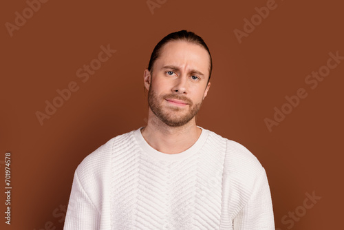 Photo of doubtful unsure man wear white sweater suspiciously looking you isolated brown color background