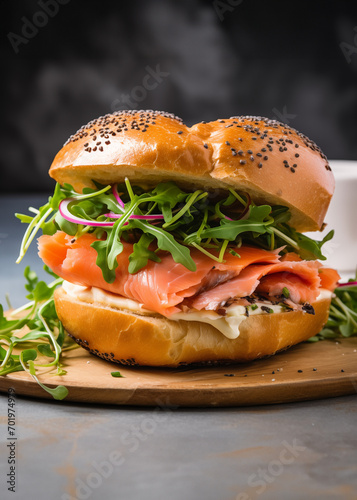 bagel sandwich with salmon and arugula on the grey table