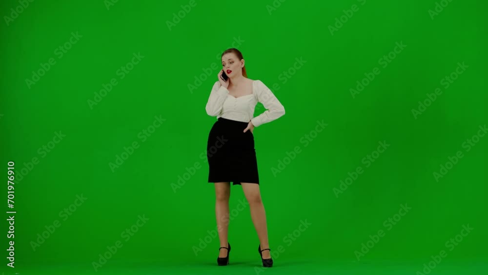 Portrait of attractive office girl on chroma key green screen. Woman in skirt walking around and talking on smartphone, frustrated expression. Portrait of attractive office girl on chroma key green screen. Woman in skirt walking around and talking on smartphone, frustrated expression.