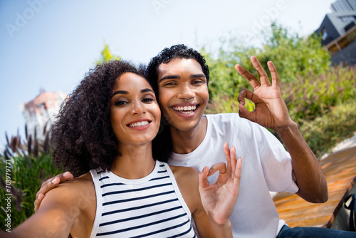 Photo of attractive cheerful black skin boyfriend girlfriend on honeymoon vacation recommend travel trip show okey sign summer outdoors photo