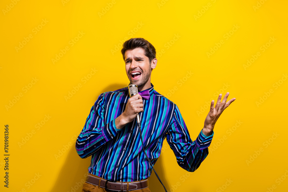 Photo of handsome man dressed striped shirt bow tie sing pop song in microphone on scene at party isolated on yellow color background - obrazy, fototapety, plakaty 