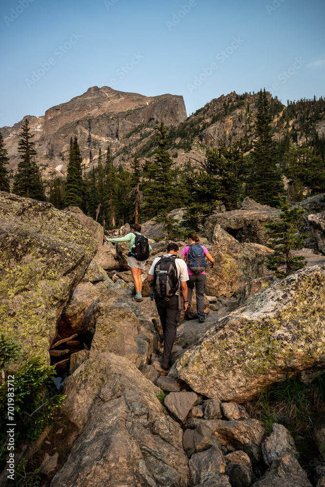 Fototapeta premium Hikers Climb Over Boulders to Haiyaha Lake
