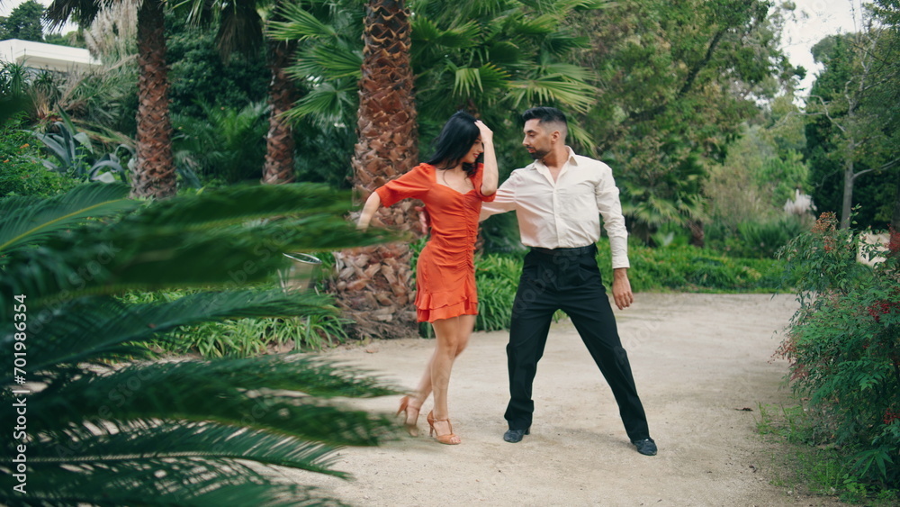 Professional artists dancing latin american dance in garden. Partners performing
