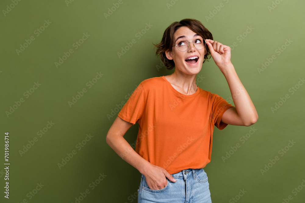 Photo of nice girl with bob hairdo dressed orange t-shirt touch glasses look at discount empty space isolated on khaki color background Photo of nice girl with bob hairdo dressed orange t-shirt touch glasses look at discount empty space isolated on khaki color background