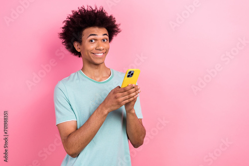Photo of tricky excited man dressed blue t-shirt chatting instagram twitter telegram facebook empty space isolated pink color background