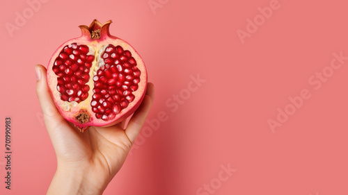 Hand holding sliced pomegranate fruit isolated on pastel background photo