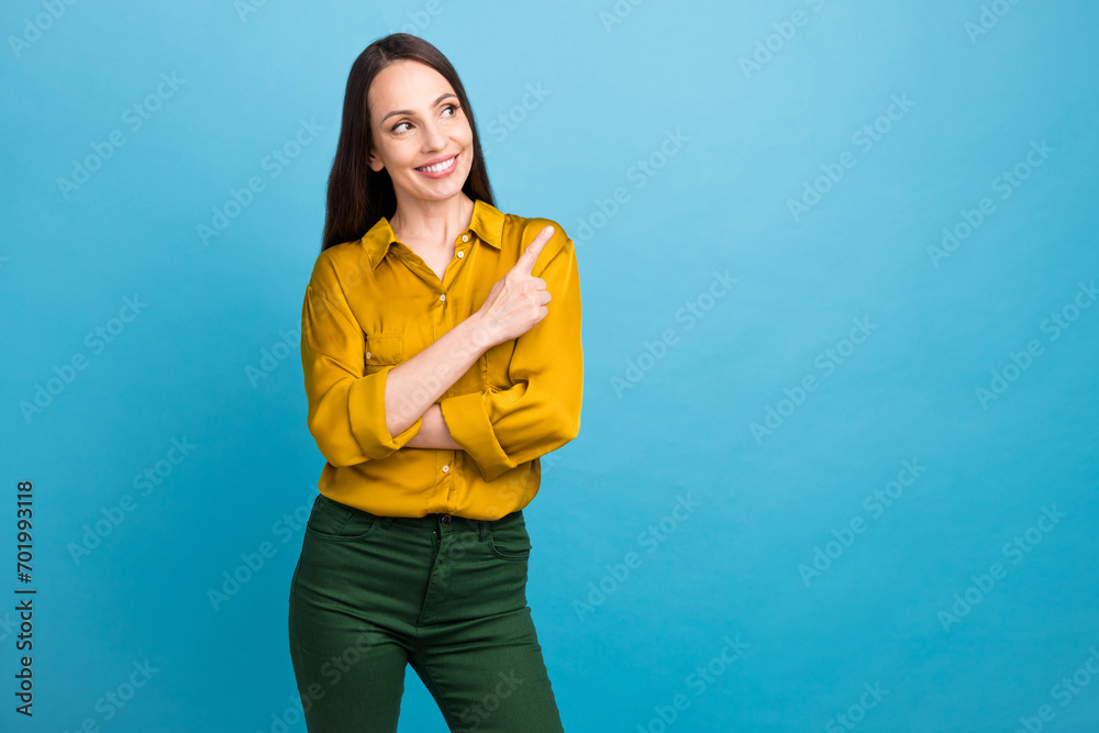 Photo of dreamy positive lady wear yellow shirt pointing finger looking empty space isolated blue color background Photo of dreamy positive lady wear yellow shirt pointing finger looking empty space isolated blue color background