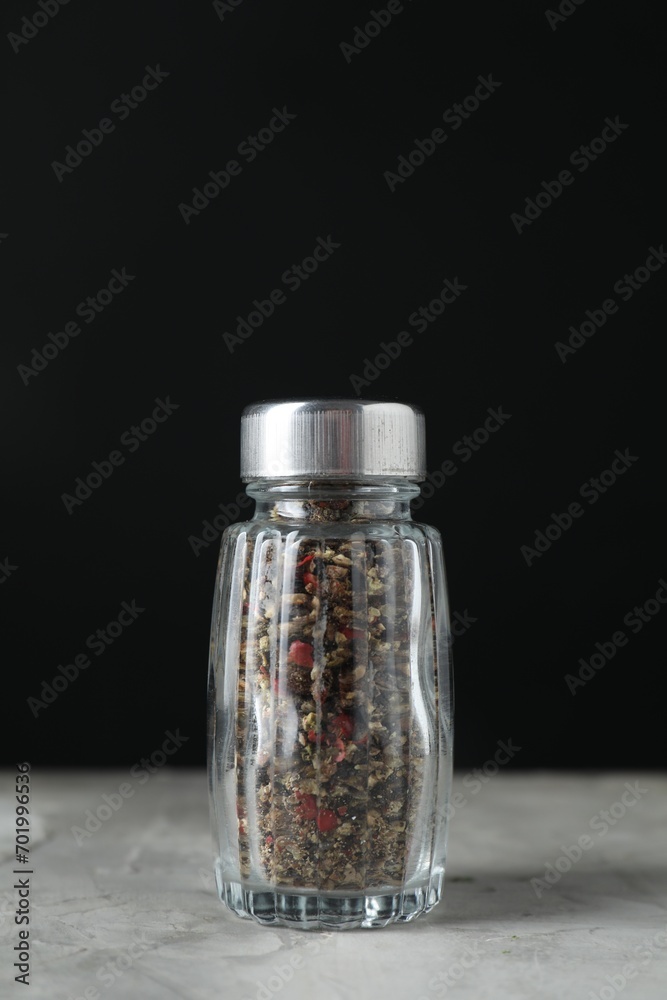 Pepper shaker on light textured table against black background Pepper shaker on light textured table against black background
