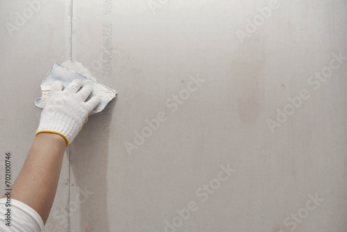 Plasterwork and wall painting preparation. close up hand of craftsman applying filling drywall patch.