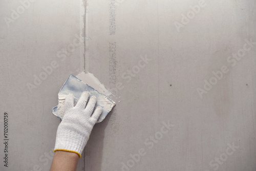 Plasterwork and wall painting preparation. close up hand of craftsman applying filling drywall patch. photo