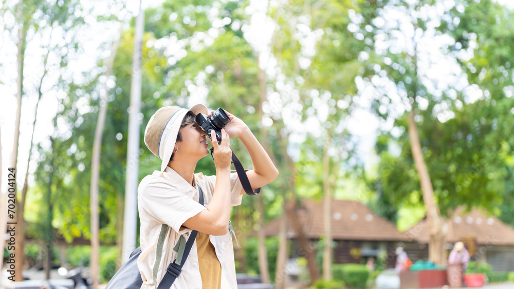 Asian non binary people relax and enjoy outdoor lifestyle travel forest mountain on summer holiday vacation. Generation z LGBTQ person using digital camera taking picture of beautiful nature in forest Asian non binary people relax and enjoy outdoor lifestyle travel forest mountain on summer holiday vacation. Generation z LGBTQ person using digital camera taking picture of beautiful nature in forest