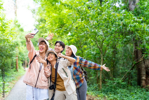 Group of Young Asian man and woman friends travel nature on summer holiday vacation. Happy people enjoy and fun outdoor lifestyle using digital camera taking picture together at forest mountain. photo