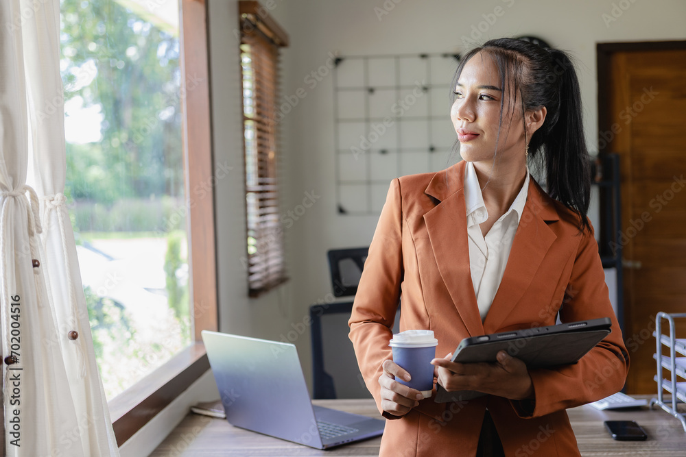 A successful businesswoman with a business stands in front of her desk engaged. A successful businesswoman with a business stands in front of her desk engaged.