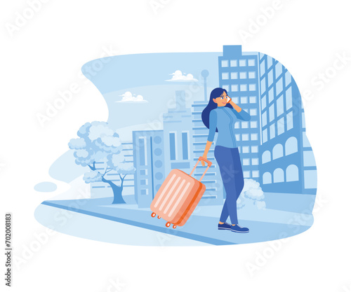 Ready for a business trip. A businesswoman walking along a city street is holding a suitcase and making a call with her cell phone. Happy, calm, peaceful girl volunteer concept. 