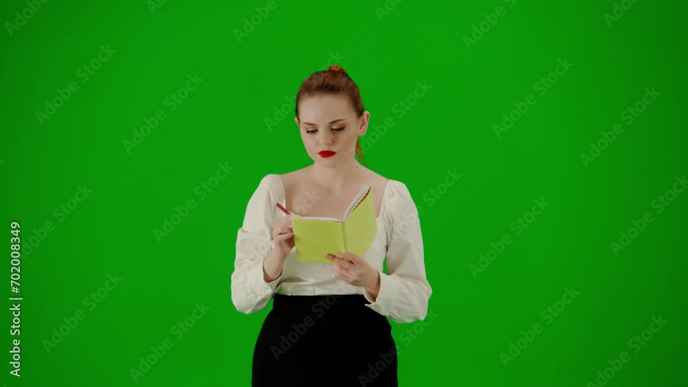 Portrait of attractive office girl on chroma key green screen. Woman in skirt and blouse walking holding notebook and writing ideas, focused face. Portrait of attractive office girl on chroma key green screen. Woman in skirt and blouse walking holding notebook and writing ideas, focused face.