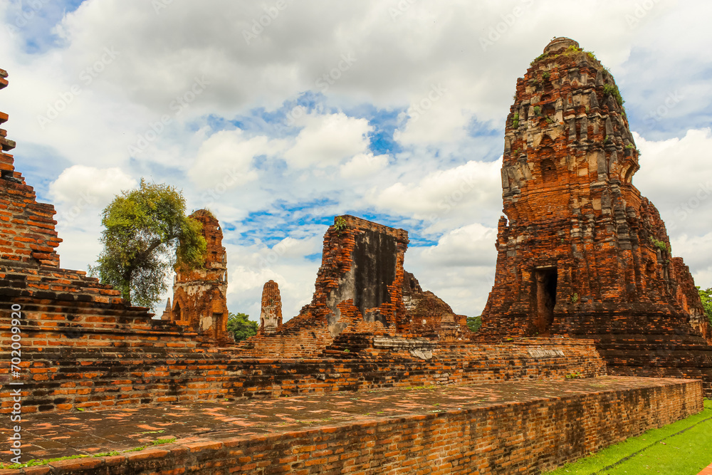 Wide view of Wat Mahathat in Sukhothai, Thailand with white puffy clouds