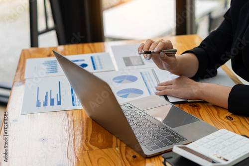 Accountant using calculator with laptop computer, budget and loan documents, Asian businesswoman meeting online to discuss project plans and financial results in office, close-up shot