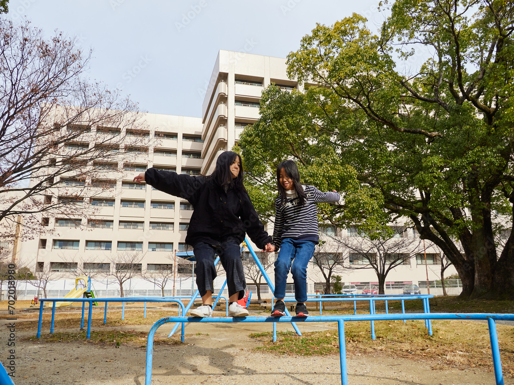 Fototapeta premium 冬の公園で楽しく遊んでいる子供姉妹の姿
