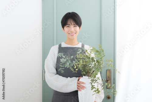 花瓶を持つ花屋のショップ販売員や家庭菜園の女性のイメージ カメラ目線の笑顔