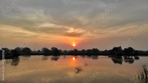 Natural view background of a lake and tree during cloudy sunset