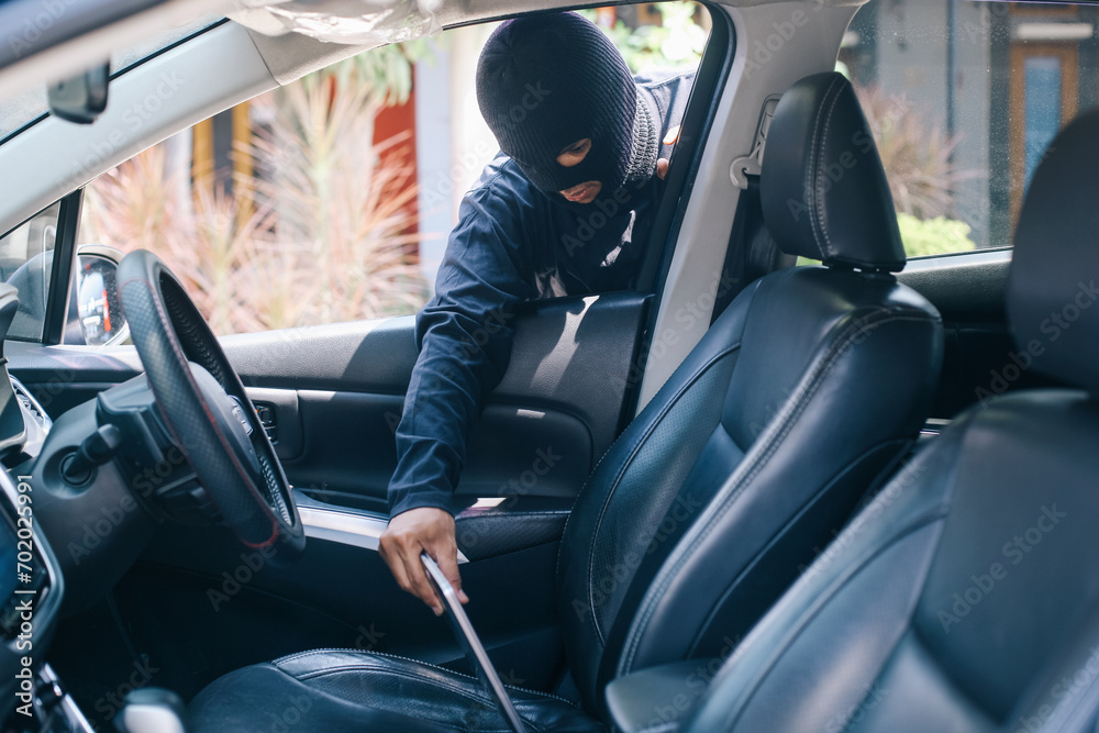 © Gatot - A thief thrust his hand out of the car window and takes a gadget device