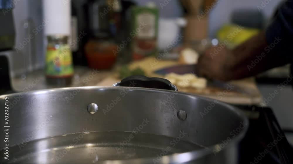 Boiling water in pot in foreground with chopping ingredients in background Boiling water in pot in foreground with chopping ingredients in background