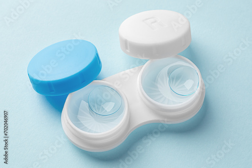 Contact lenses in case with solution liquid on light blue background