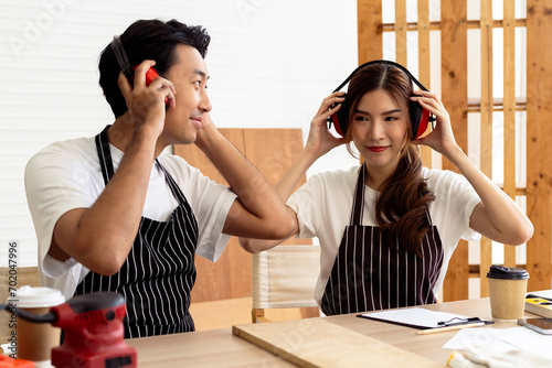 Two carpenters wearing safety headsets while woodworking in workshop, protect hearing using ear protection photo