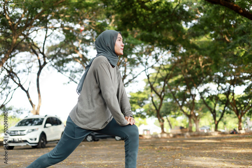 asian muslim woman sports clothing and hijab stretching in park