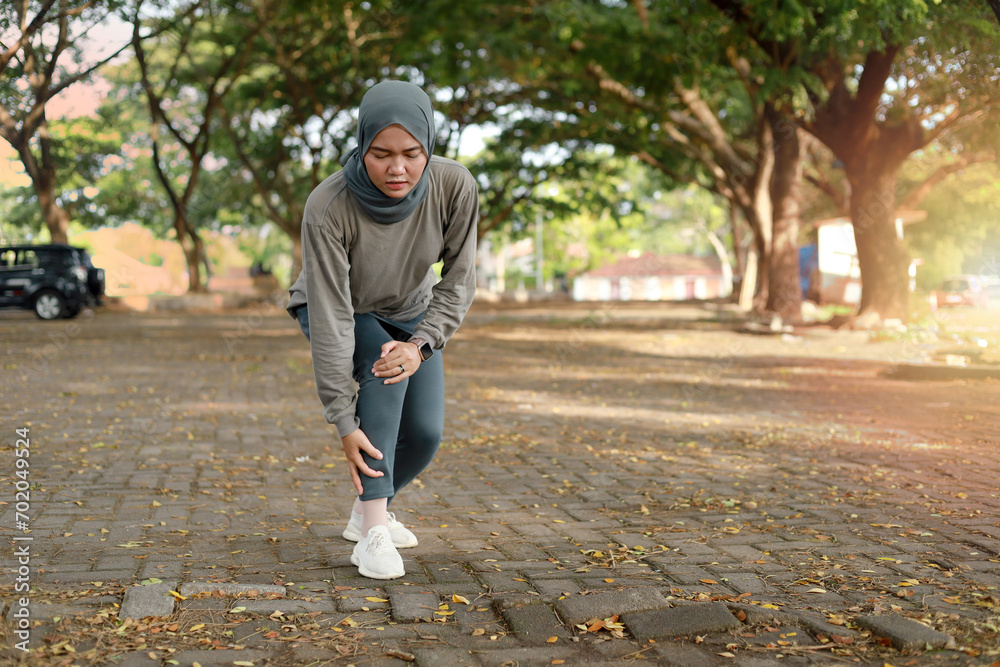 Fototapeta premium Over trained injured asian muslim woman when training exercising or running outdoors. Ankle twist sprain accident in sport exercise running jogging