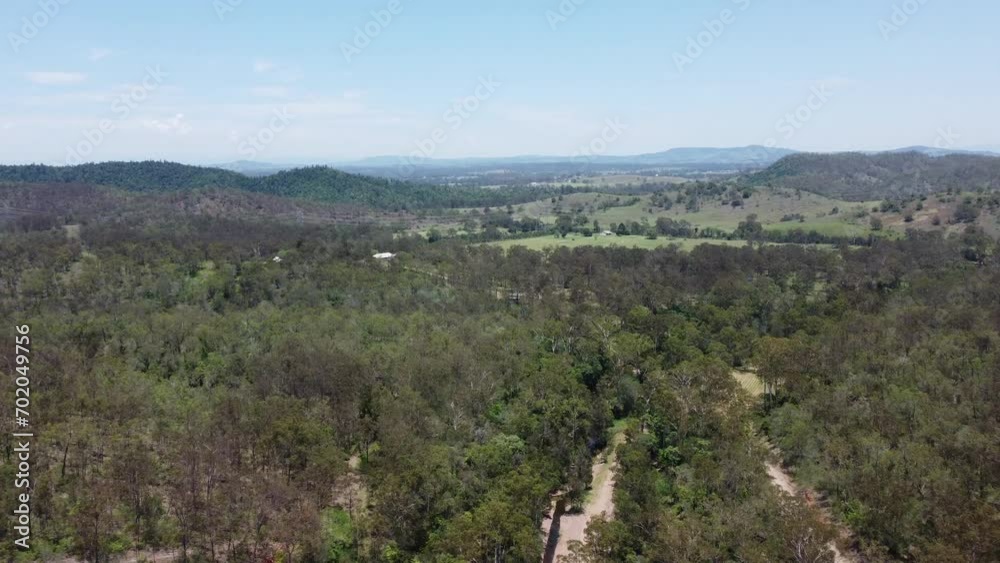 Aerial view of a forest showing mountains and a green field with a private house in the background Aerial view of a forest showing mountains and a green field with a private house in the background