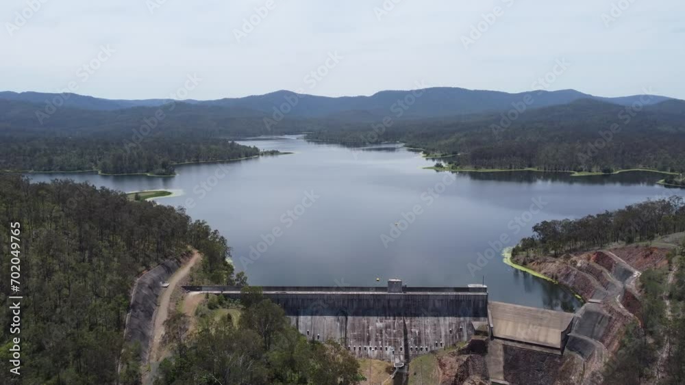 Aerial view of a dam and a dam wall with mountains in the background Aerial view of a dam and a dam wall with mountains in the background