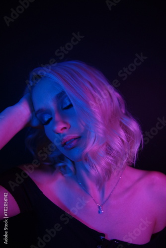 Captivating Blonde Elegance: Short-Haired Beauty in Off-the-Shoulder Black Shirt, Illuminated by Vibrant Blue and Red Lights on a Stylish Black Background