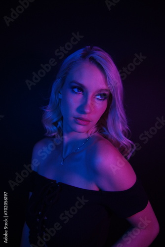 Captivating Blonde Elegance: Short-Haired Beauty in Off-the-Shoulder Black Shirt, Illuminated by Vibrant Blue and Red Lights on a Stylish Black Background © Baili