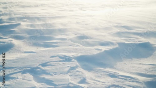 The wind is driving snow across the snow cover. Close-up of flying snow on a snow-covered surface.