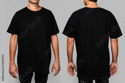 Front and back views of a man wearing a black, oversized t-shirt with blank space, ideal for a mockup, set against gray background photo