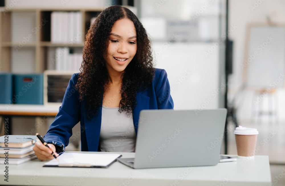 Beautiful woman using laptop and tablet while sitting at her working place. Concentrated at work. Beautiful woman using laptop and tablet while sitting at her working place. Concentrated at work.