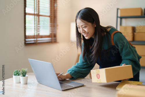 Starting small business entrepreneur of independent young Asian woman online seller is using computer and taking orders to pack products for delivery to customers. SME delivery concept © Jirapong
